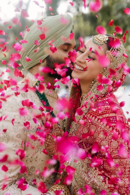 Beautiful just married shot of the couple under a shower of rose petals